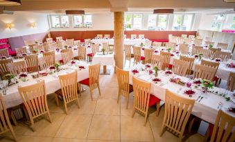 a large dining room with multiple tables and chairs arranged for a group of people at Gasthof Zur Post