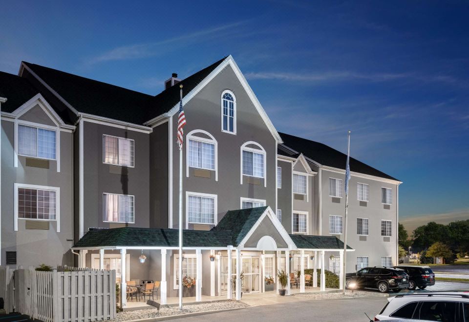 a large hotel building with multiple flags flying , surrounded by cars parked in front of it at Country Inn & Suites by Radisson, Toledo, Oh