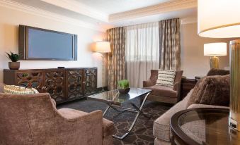 a living room with a large flat - screen tv mounted on the wall , surrounded by comfortable couches and chairs at Hilton Concord