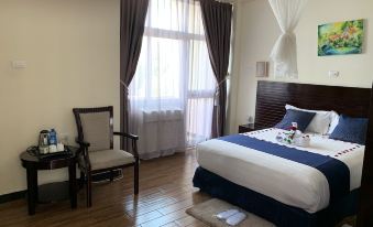 a well - furnished hotel room with a king - sized bed , a dining table , and a chair near a window at Delano Hotel Bahir Dar