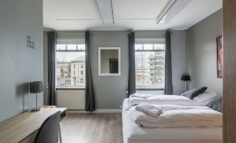 a modern bedroom with two beds , one on each side of the room , and a window overlooking a cityscape at Acco Town Square Apartments