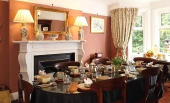 a dining room with a round dining table surrounded by chairs , and a fireplace in the background at Lisnacurran