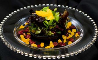 a silver plate with a salad and various fruits is presented on a black tray at The Castle at Skylands Manor