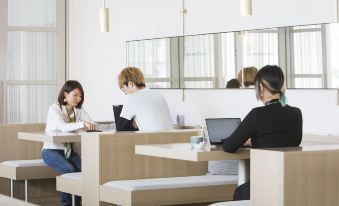 a group of people working in an office , with some sitting at desks and others working on laptops at Hotel Anteroom Naha