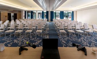 a conference room with rows of chairs and a laptop on a table , ready for a presentation at Doubletree by Hilton Milan Malpensa Solbiate Olona