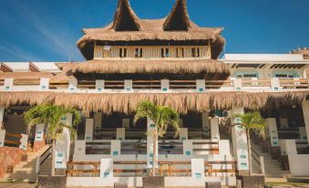 a wooden building with a thatched roof is surrounded by palm trees and has a seating area at Riviera Del Sol Hotel Spa