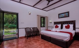 a modern , white bedroom with red accents and wooden furniture , featuring a large bed , two chairs , and a sliding glass door at Paradise Resorts