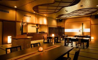 a dimly lit restaurant with wooden tables and chairs , a bar , and a fireplace in the background at Shosenkaku Kagetsu