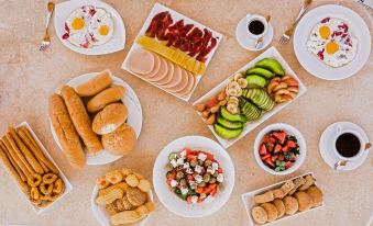 a table is filled with various types of food , including sandwiches , fruit , and bread , arranged in white plates at Desert Moon