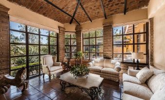 a spacious living room with high ceilings , wooden beams , and brick walls , featuring comfortable seating arrangements and large windows at Quinta San Carlos