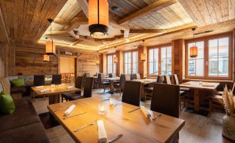 a wooden restaurant with tables and chairs , large windows , and hanging light fixtures , giving it an inviting atmosphere at Hotel Adler - Paulas Alb