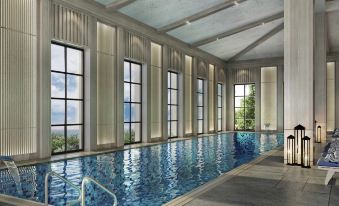 a large indoor swimming pool with multiple windows , allowing natural light to fill the space at Rixos Water World Aktau