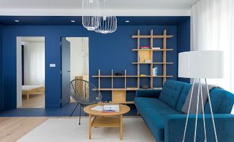 a modern living room with a blue couch , a coffee table , and a bookshelf filled with books at Colors Apartments