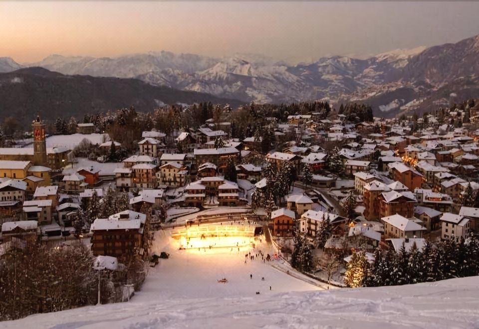 a snowy ski slope with skiers and snowboarders enjoying their time on the slopes at night at Harmony Suite Hotel