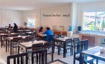 a restaurant with wooden tables and chairs , people sitting at the tables , and a wall with thai writing at Tokyo Hotel