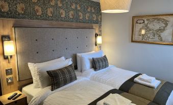 a hotel room with two beds , one on the left and one on the right side of the room at Queens Head Inn