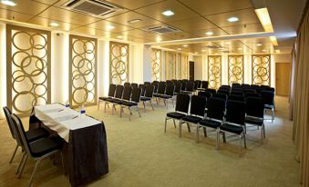 a large conference room with rows of chairs arranged in a semicircle , and a podium at the front of the room at Pinetree Hotel
