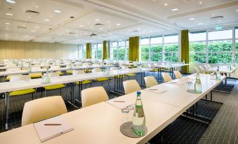 a conference room with white tables , green curtains , and a bottle of water on the table at Select Hotel Erlangen