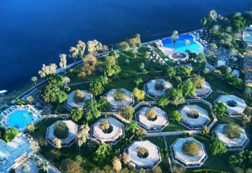 an aerial view of a resort with multiple buildings , surrounded by trees and a body of water at Jolie Ville Hotel & Spa Kings Island Luxor