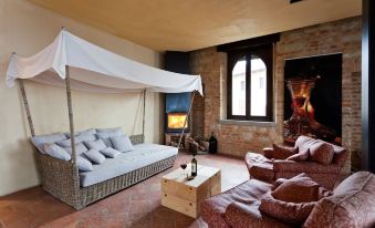 a cozy living room with a large window , stone fireplace , and white canopy over a wicker couch at Castello di Gabiano