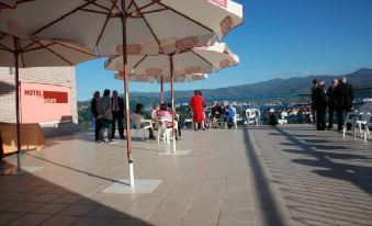 a group of people sitting under umbrellas on a patio overlooking a body of water at Hotel Novo