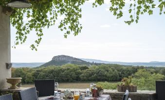 a table is set with a view of a mountain and trees , overlooking a river at Chambre d'Hotes