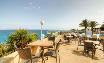 a rooftop patio with tables and chairs , overlooking the ocean , under a clear blue sky at Hotel Club Sunway Punta Prima
