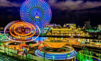 a nighttime amusement park with various rides and attractions , including a ferris wheel and a carousel at Oakwood Suites Yokohama