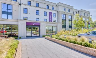 a modern building with a purple banner , surrounded by trees and other buildings , under a clear blue sky at Premier Inn Bangor (Northern Ireland)