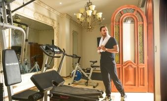 a man in a gym , standing in front of various exercise equipment and equipment , with a chandelier hanging from the ceiling at San Juan Hotel