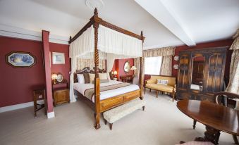 a spacious bedroom with a four - poster bed in the center , surrounded by various furniture and decorations at The Holt Hotel