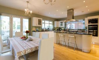 a large , open kitchen with a dining table and chairs , as well as a breakfast bar at Leafy Suburban Bed and Breakfast