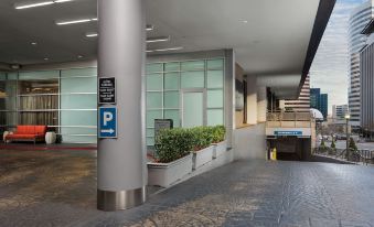 a long , narrow walkway with stairs leading up to a parking garage entrance , surrounded by potted plants and signs at Hyatt Centric Arlington