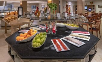 a dining table filled with a variety of food items , including fruits , vegetables , and meats at Hotel Las Vegas