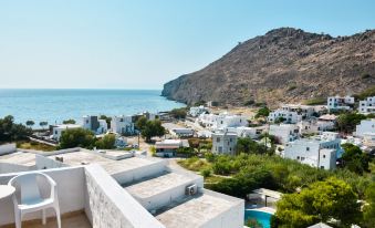 a rooftop view of a white building overlooking the ocean , with a swimming pool in the foreground at Anamar Patmos