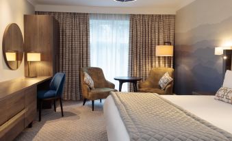 a hotel room with a bed , two chairs , and a desk , all situated in a well - lit area at Mercure Blackburn Dunkenhalgh Hotel & Spa