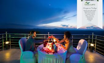 a man and a woman are sitting at a dining table on a balcony overlooking the ocean , enjoying a romantic dinner at Coorg Cliffs Resort