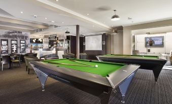 a room with two green pool tables , one on the left and the other on the right , surrounded by chairs at Granville Hotel