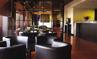 a modern restaurant with black leather chairs and tables , large windows , and a bar area at AquaHotel