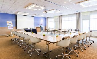 a large conference room with a long table and several chairs arranged for a meeting at Novotel Maastricht