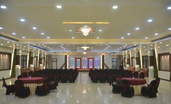 a large banquet hall with multiple rows of tables and chairs , as well as chandeliers hanging from the ceiling at Leisure Resort
