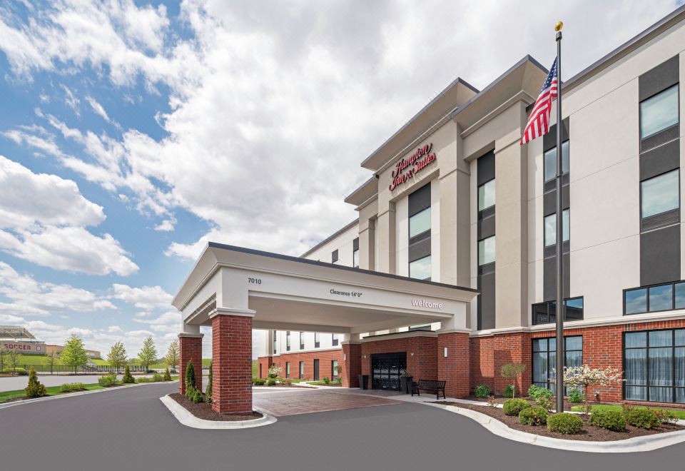 a hotel entrance with a large american flag and an entrance gate that serves as the pedestrian bridge at Hampton Inn & Suites Bridgeview Chicago