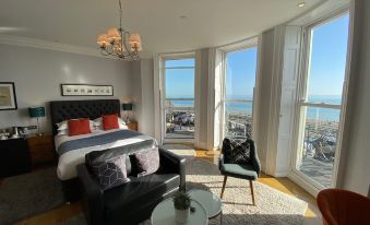 a modern bedroom with large windows offering views of the ocean , a comfortable bed , and a black leather couch at A Room with A View