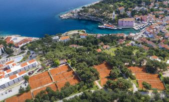 aerial view of a red clay beach with tennis courts , houses , and a harbor in the background at Vitality Hotel Punta