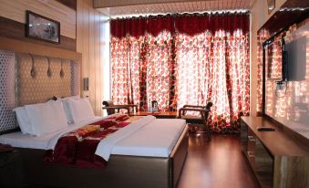 a cozy bedroom with a large bed , white sheets , and red curtains , along with a couch and other furniture at Hotel President