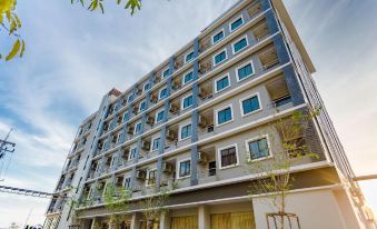 a modern apartment building with multiple floors and balconies , set against a blue sky at Grand Inter Hotel