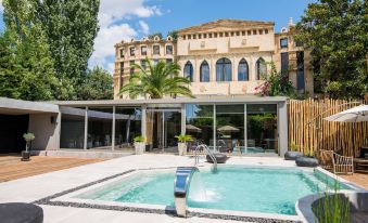 a large swimming pool is situated in front of a building with a glass roof at Mikelina Boutique Hotel