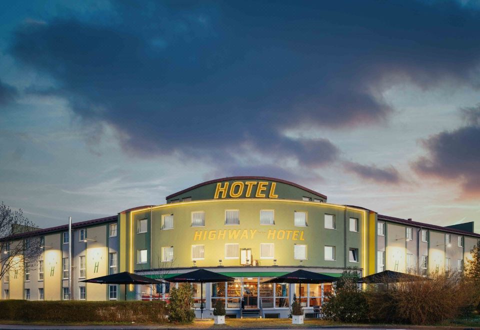 "a large hotel building with a yellow sign that reads "" hotel "" prominently displayed on the front of the building" at Highway Hotel