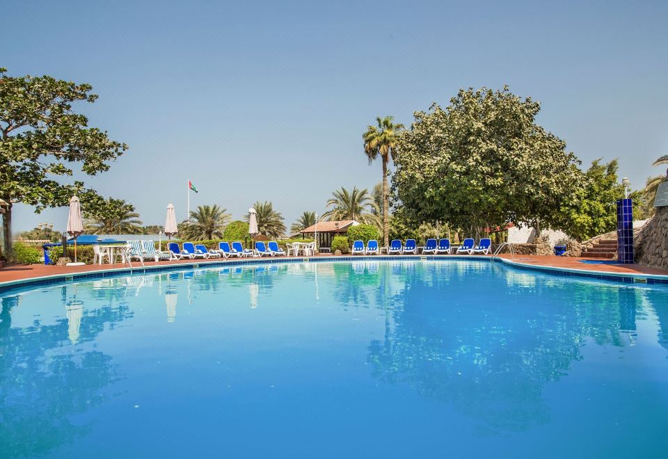 a large outdoor swimming pool surrounded by lounge chairs and umbrellas , providing a relaxing atmosphere at Marbella Resort