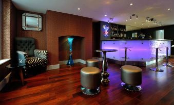 a room with wooden floors , purple lights , and various furniture including chairs , stools , and tables at Victoria Hotel